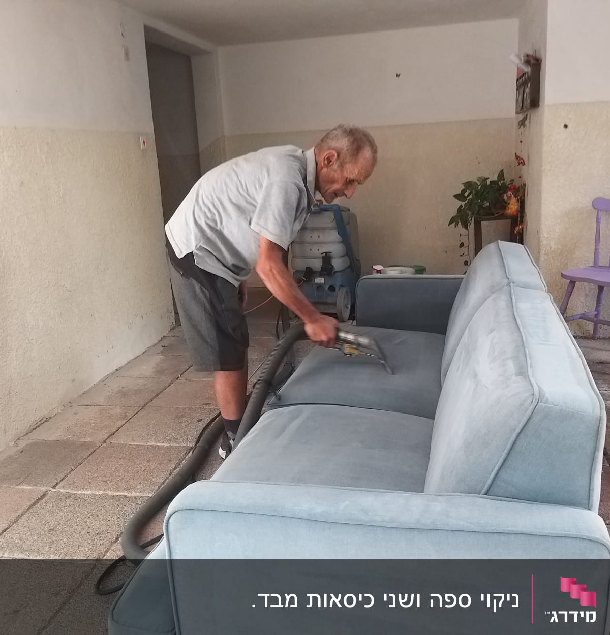 אדם מנקה ספה עם שואב אבק